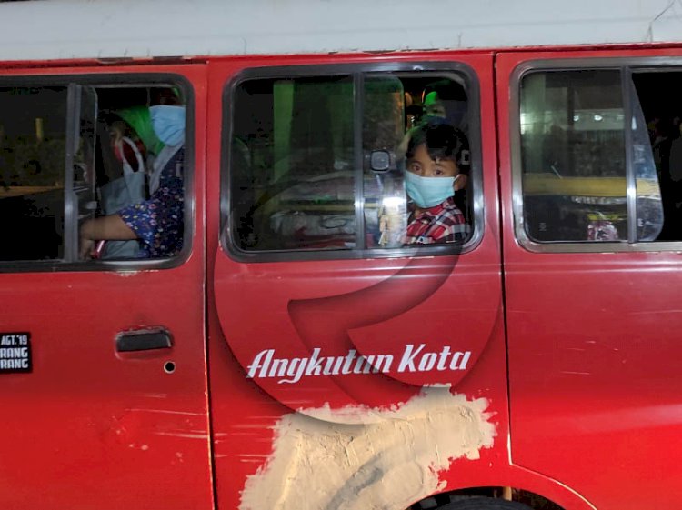 Seorang bocah yang terlihat menggunakan masker saat barada di dalam angkutan kota. (rmolsumsel.id/M Hatta)