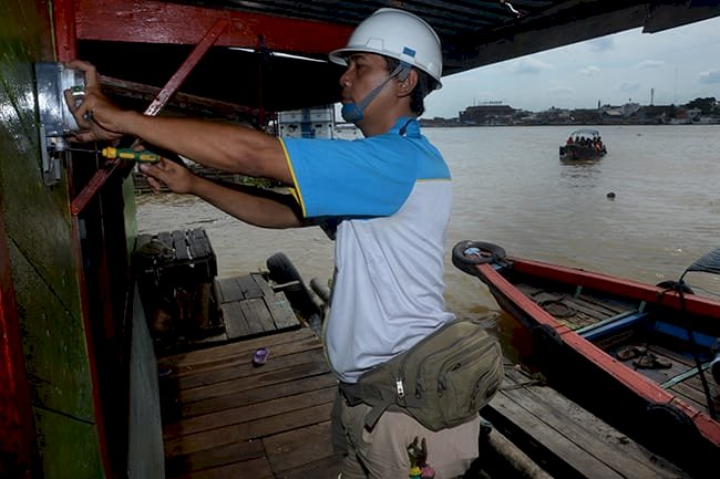 Petugas PLN tengah memasang listrik di rumah rakit atau terapung yang berada di bantaran Sungai Musi Kota Palembang. Foto: M Hatta/rmolsumsel.id