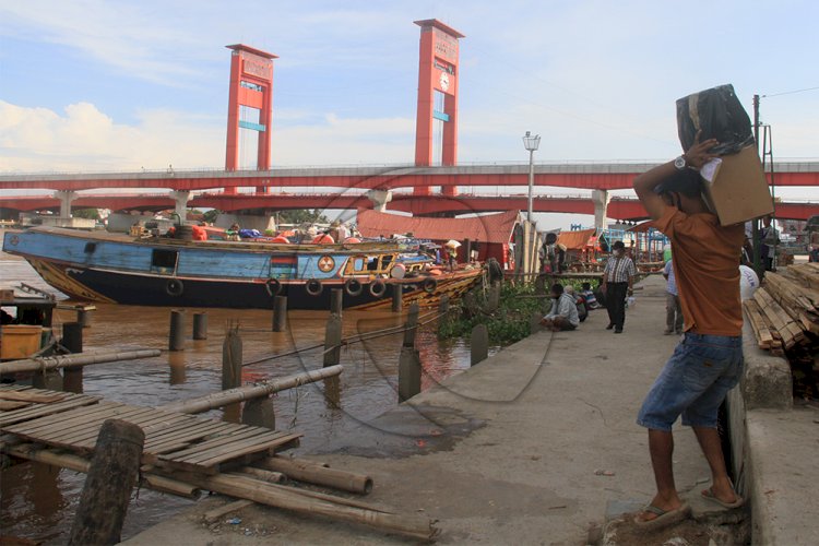 Sejumlah kuli angkut barang tengah mengangkut barang ke kapal yang parkir di pinggir  Dermaga Pasar 16 Ilir. (m hatta/rmolsumsel.id)