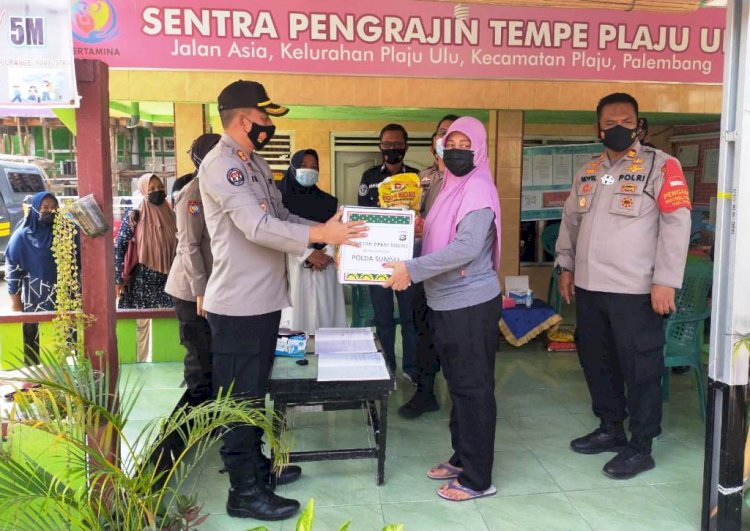 Kasubbid Penmas Polda Sumsel AKBP Iralinsah menyerahkan bantuan kepada perwakilan warga Kelurahan Plaju Ulu. (Humas Polda Sumsel/rmolsumsel.id)