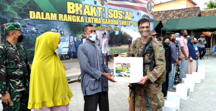 Seorang anggota US Army peserta latihan bersama Garuda Shield-15/2021 menyerahkan bantuan paket Sembako kepada perwakilan warga Dusun Talang Sipin. (Ist/rmolsumsel.id)