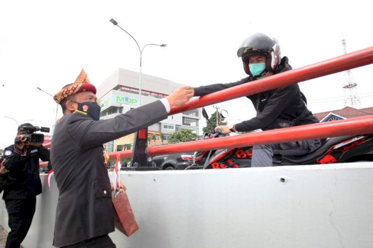 Wakapolda Sumsel Brigjen Rudi Setiawan membagikan telok abang kepada pengendara di flyover Polda Sumsel. (Ist/rmolsumsel.id)