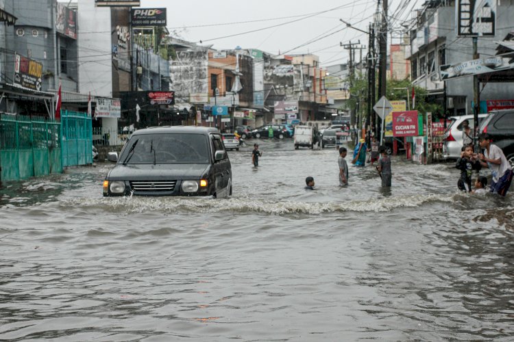 Sebuah mobil menerobos genangan air di Jalan Mayor Ruslan Batubara, Rabu (1/9). Sejumlah anak-anak memanfaatkan genangan air untuk bermain. (Humaidy Kennedy/rmolsumsel.id)