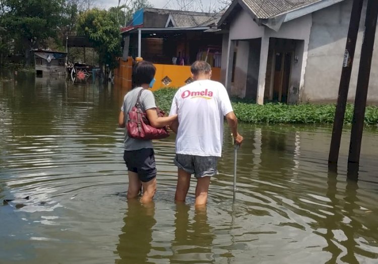 Yeni Warga Blok L Perumahan Griya Buana Indah II saat mengantar suaminya berobat ditengah genangan air yang tak kunjung surut selama tiga bulan. (Istimewa/rmolsumsel.id)