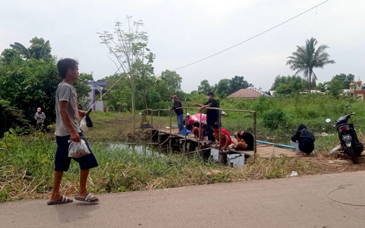 Banyak warga memancing di aliran anak sungai Jl Irigasi,  memanfaatkan sisa banjir besar di Palembang beberapa hari lalu. (rmolsumsel)