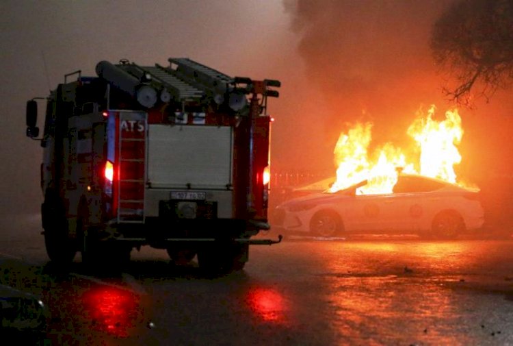 Mobil Damkar melintas di dekat mobil polisi yang terbakar selama protes terhadap kenaikan harga bahan bakar di Kazakhstan, Rabu (5/1). (REUTERS/Pavel Mikheyev/rmolsumsel.id)