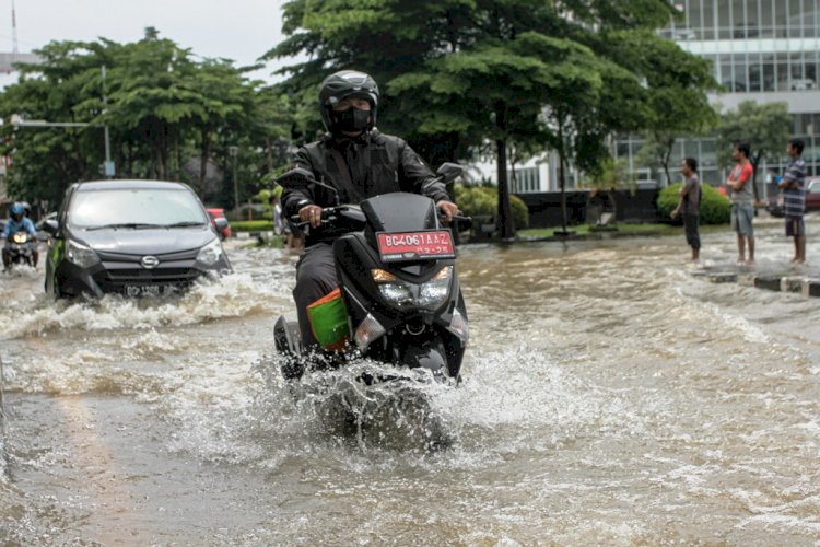 Seorang pengendara sepeda motor menerobos banjir di salah satu jalan protokol Kota Palembang belum lama ini. (Humaidy Kenedy/rmolsumsel.id)