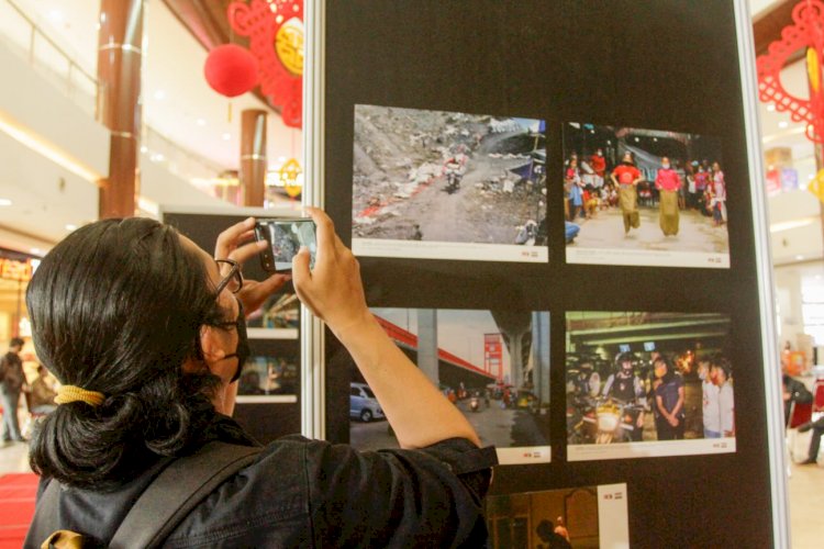 Pengunjung memotret karya foto yang ditampilkan dalam paneran foto bertema adaptasi yang digelar PFI Palembang di OPI Mall. (Humaidy Aditya Kenedy/Rmolsumsel.id). 