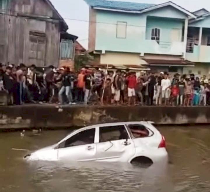 Satu unit mobil diamuk massa dan diceburkan di aliran anak Sungai Musi. (Ist/rmolsumsel.id)