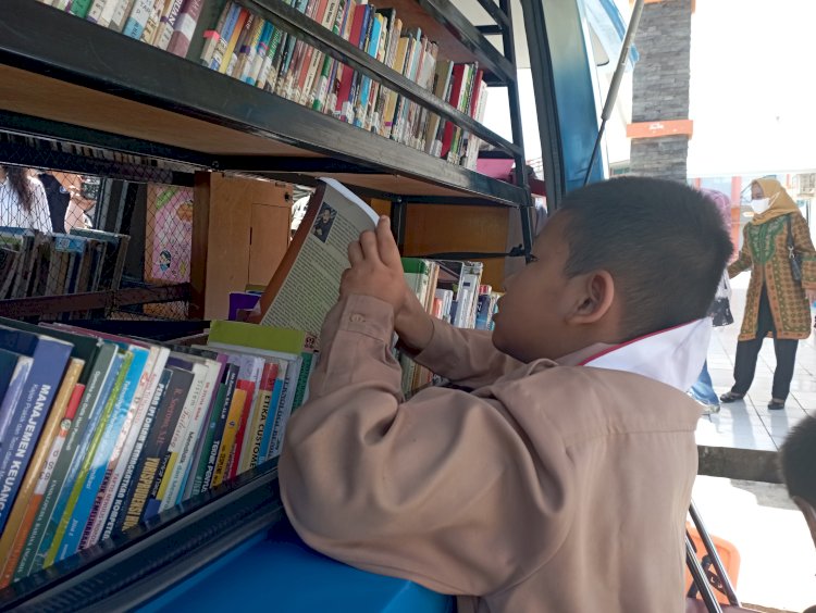Seorang murid Sekolah Dasar (SD) tengah memanfaatkan fasilitas perpustakaan keliling yang disediakan Dinas Perpustakan Provinsi Sumsel. (Mita Rosnita/rmolsumsel.id)