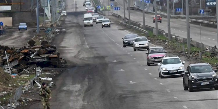 Konvoi mobil yang mengevakuasi warga sipil melewati tank Rusia yang hancur di pinggiran Buzova/Net