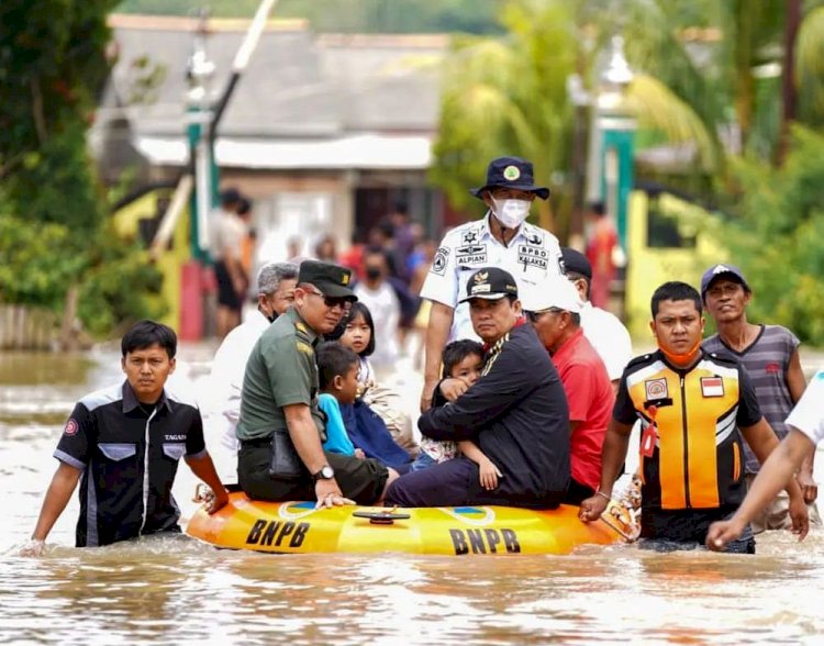 Bupati Banyuasin Askolani mendekap seorang anak yang kedinginan usai rumahnya terendam banjir. (Diskominfo Banyuasin/rmolsumsel.id)  