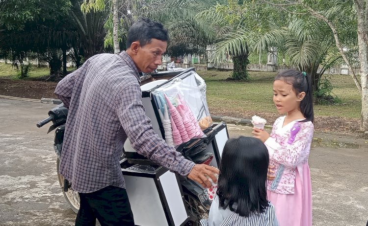 Yusirman Syah menjajahkan dagangannya kepada anak-anak, penjual es tong-tong asal desa Ujan Mas, Kabupaten Muara Enim ini berhasil menyekolahkan anaknya hingga meraih Magister Hukum dari universitas ternama di Sumatera Selatan/Foto:Noviansyah