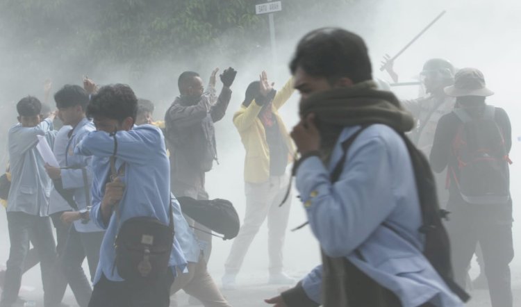 Seorang mahasiswa menutup wajahnya sembari berlari saat petugas menyemprotkan APAR untuk memadamkan api dari ban bekas yang dibakar mahasiswa, Kamis (8/9/2022). (Humaidy Kennedy/rmolsumsel.id)