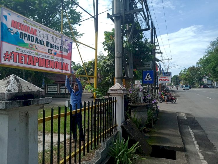 ampak pengurus Abdi Lestari Reza Ade Sanur memasang spanduk menolak hasil Pilwabup Muara Enim.