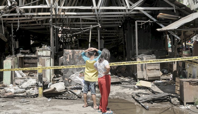 Dua warga yang melihat kios di Pasar Cinde yang terbakar Minggu malam, Senin (28/11/2022).( Adam rachman/RmolSumsel.id)