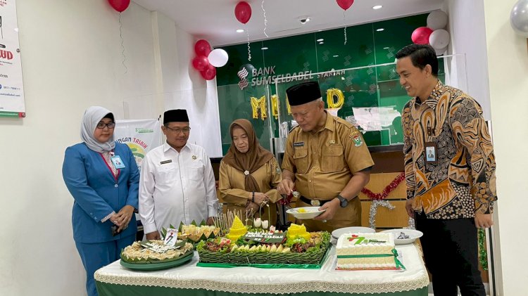 Pj Sekda Muara Enim Riswandar didampingi Pimpinan BSB Syariah Cabang Muara Enim Mgs M Mardian (baju batik), menyerahkan tumpeng kepada nasabah BSB Syariah. (noviansyah/rmolsumsel.id)