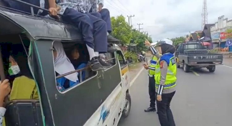 Tampak petugas Lantas Polres Muara Enim menghentikan kendaraan dan meminta semua pelajar turun dari atap mobil.