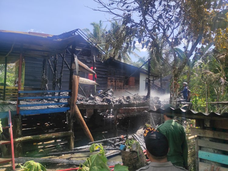 Petugas dibantu warga melakukan pemadaman api di rumah korban/ist.