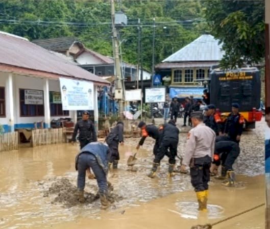 Polisi membantu warga terdampak banjir bandang untuk membersihkan lumpur. (ist/RmolSumsel.id)