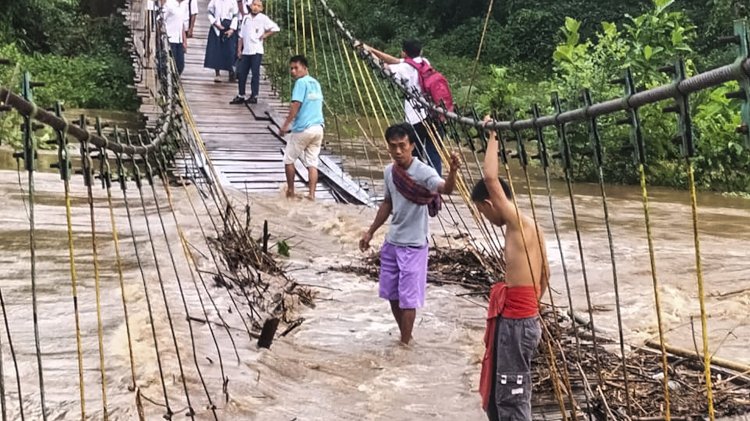 Lokasi banjir di Desa Rantau Kumpay di Kecamatan Sosoh Buay Rayap, Kabupaten Ogan Komering Ulu (OKU), Sumatera Selatan membuat jembatan gantung nyaris putus. (Amizon.RmolSumsel.id)