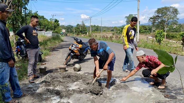 Warga Talang Banyu, Kabupaten Empat Lawang, Sumatera Selatan bergotong royong memperbaiki jalan rusak yang sering menyebabkan kecelakaan di kawasan Jalan Noerdin Pandji atau jalan Poros Tebing Tinggi - Pendopo.(Salim/RmolSumsel.id)