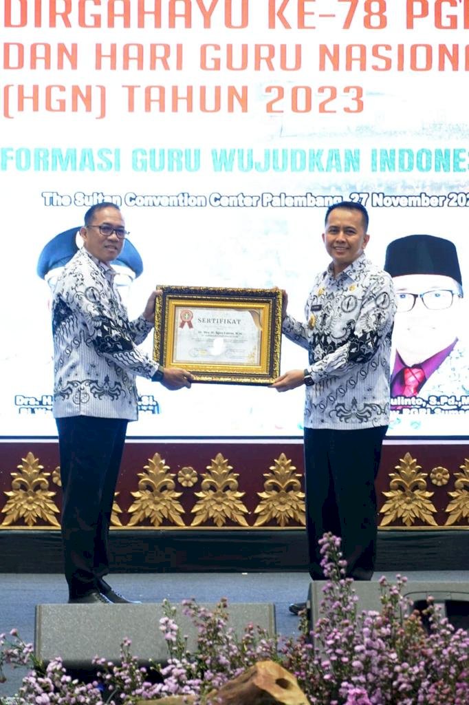 Ketua PGRI Sumsel H Ahmad Zulinto memberikan penghargaan kepada Pj Gubernur Sumsel Agus Fatoni saat Peringatan Hari Jadi ke-78 PGRI dan Hari Guru Nasional (HGN) Tahun 2023 di The Sultan Convention Center (PSCC) Palembang. (ist/rmolsumsel.id) 