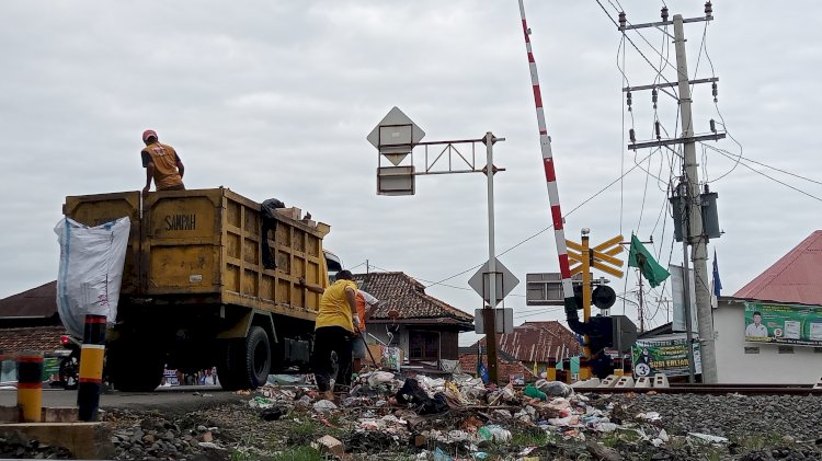 Petugas kebersihan membersihkan sampah yang menumpuk di antara jalur kereta api. (Noviansyah/rmolsumsel.id)