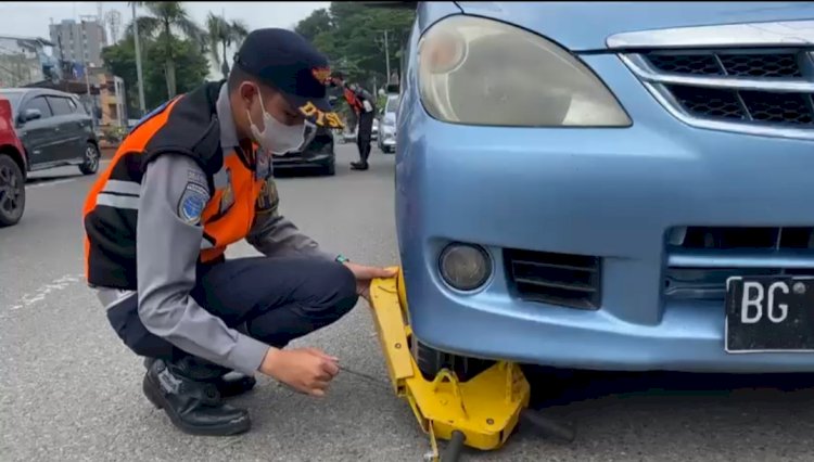 Petugas Dishub Kota Palembang menggembok mobil yang parkir sembarangan di depan rumah sakit umum Mohammad Hoesin Palembang. (Fauzi/RMOLSumsel.id)