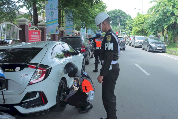 Petugas Dishub Kota Palembang saat menggembosi mobil yang parkir dibahu jalan di depan RSMH Palembang. (Fauzi/RMOLSumsel.id)