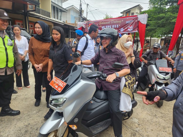 Pj Gubernur Sumsel Agus Fatoni saat membonceng sang istri menuju TPS 35. (ist/rmolsumsel.id)