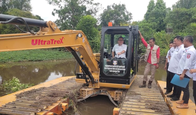 Pj Bupati Banyuasin, Hani Syopiar Rustam saat mengoperasikan alat berat untuk normalisasi Sungai Gasing. (ist/rmolsumsel.id)