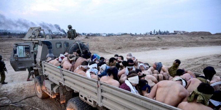 Tentara Israel berdiri di dekat truk yang penuh dengan tahanan Palestina di Jalur Gaza pada 8 Desember 2023/Net