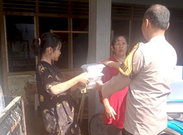 Bhabinkamtibmas Polsek Semidang Aji, Aipda Hadi Suhendra membagikan makanan siap saji kepada warga. (ist/rmolsumsel.id) 