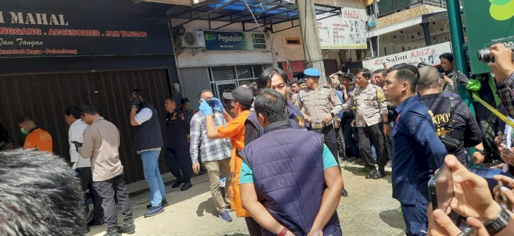 Polisi membuka paksa rolling door distro yang diduga menjadi tempat seorang debt collector dibunuh dan dikubur. (Fauzi/RMOLSumsel.id)