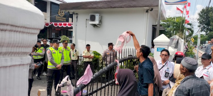 Massa menggantungkan pakaian dalam di depan halaman kantor Kejari OKI, sebagai bentuk protes atas vonis yang dijatuhkan terhadap terdakwa Ujang Kocot, Rabu (17/7). (Hari Wijaya/RMOLSumsel.id)