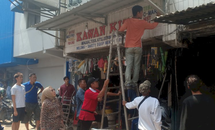 Titis Rachmawati selaku kuasa hukum pemilik tanah dan bangunan di kawasan Cinde Palembang saat melepaskan stiker pengumuman di ruko/Foto: Denny Pratama