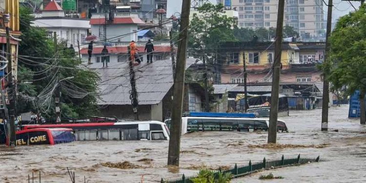 Warga memanjat atap rumah saat lingkungan tempat tinggal mereka terendam banjir setelah Sungai Bagmati meluap menyusul hujan lebat di Kathmandu, Nepal, pada Sabtu, 28 September 2024/AFP