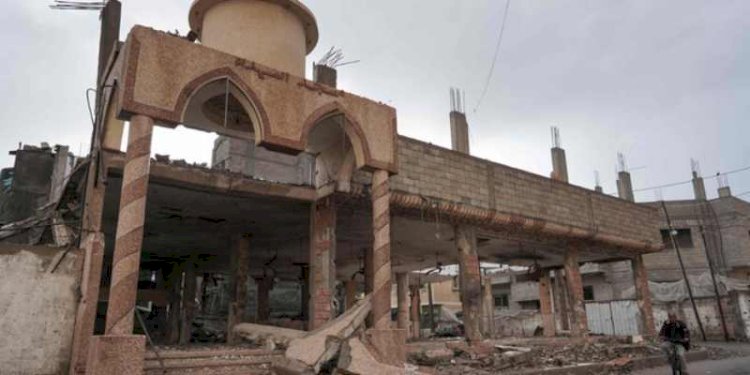 Seorang pria Palestina bersepeda melewati masjid yang hancur di Deir Al-Balah/Arab News