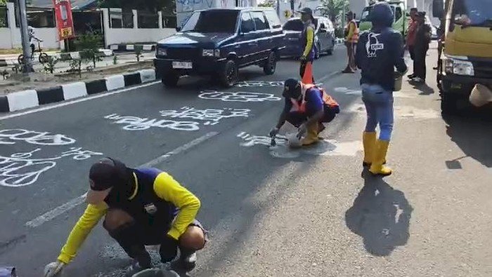 Petugas PUPR Palembang saat menghapus coretan di ruas Jalan Angkatan 45 Palembang/ist