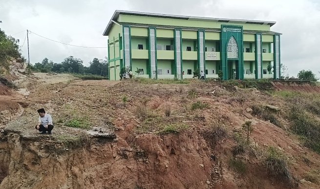 Jalan utama menuju ke sekolah putus tergerus oleh air sehingga para siswa dan guru terpaksa harus melewati jalan darurat menuju ke sekolah di jalan Trans AD. (noviansyah/rmolsumsel.id) 