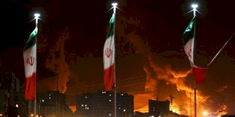 Bendera Iran berkibar saat api dan asap dari serangan Israel terhadap depot minyak Sharan membubung, menyusul serangan Israel terhadap Iran, di Teheran, Iran, 15 Juni 2025/Net